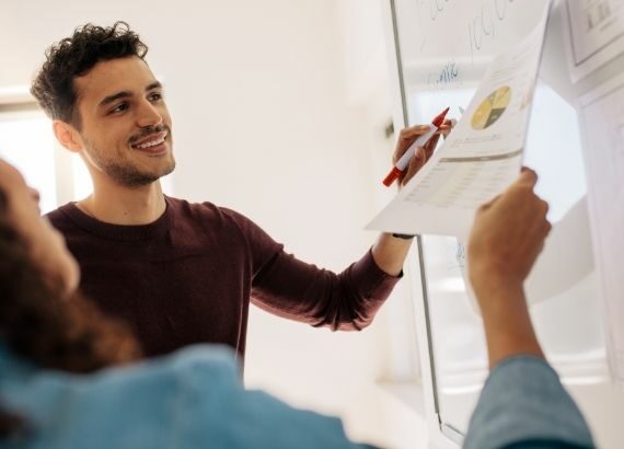 Zwei Personen vor einem Whiteboard, die gemeinsam Daten analysieren